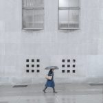 unrecognizable woman walking under rain