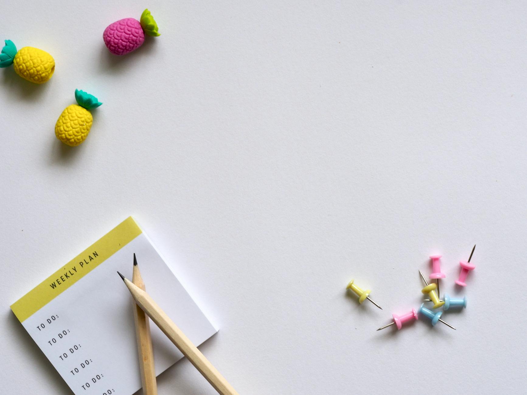 pink yellow and blue push pins and brown pencil