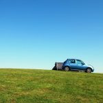 blue hatchback on green grass field under blue sky